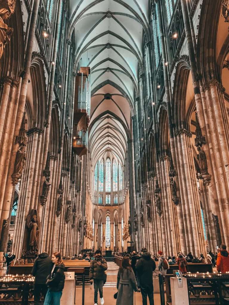 Cologne Christmas Markets with charming wooden stalls, twinkling lights, and festive decorations, set against the backdrop of the impressive Cologne Cathedral.