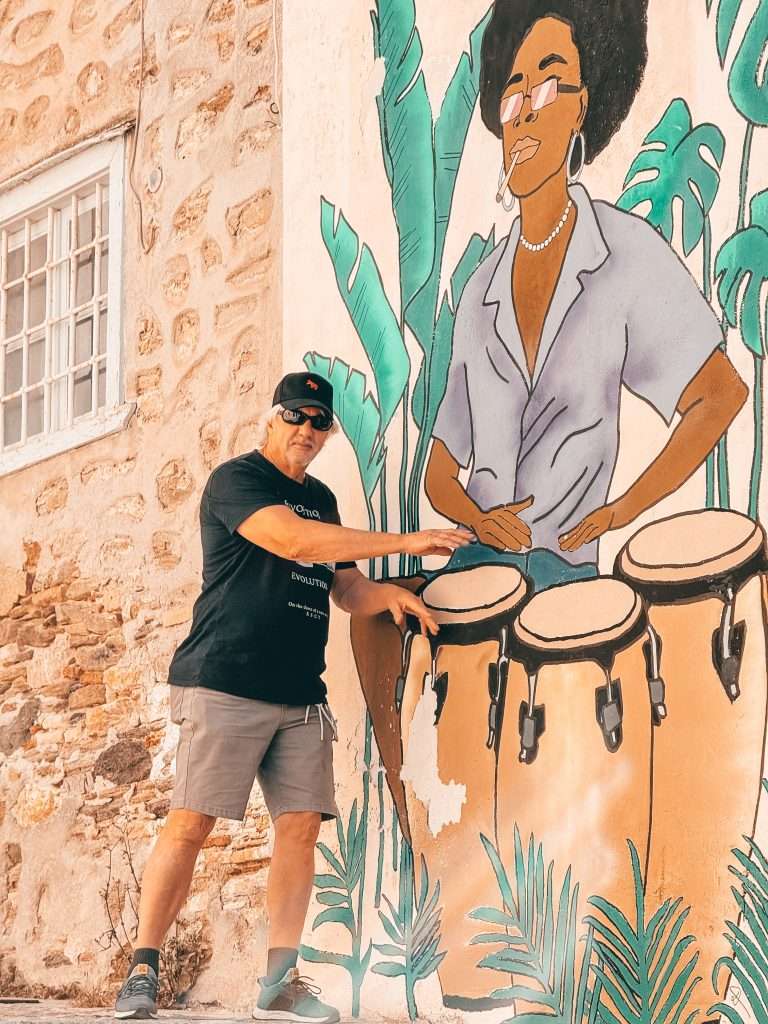 Man pretending to drum next to a Muriel in Syros