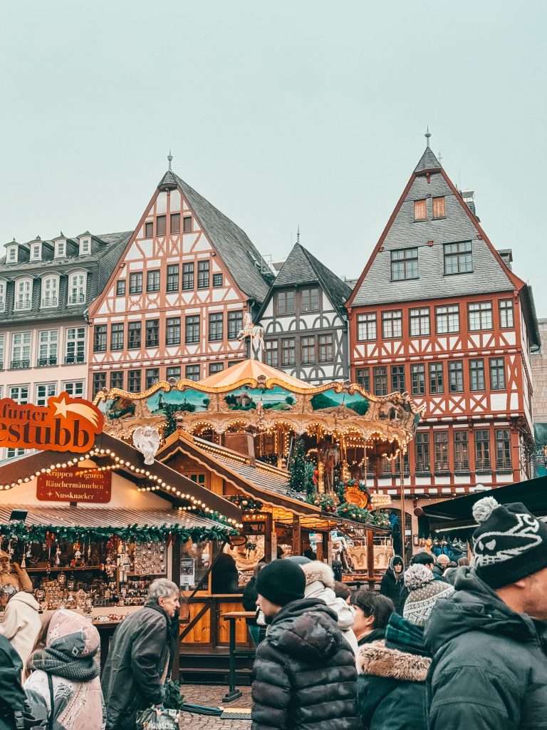 Frankfurt Christmas Markets bustling with holiday cheer, featuring traditional wooden stalls, festive lights, and seasonal decorations, with the historic architecture of the city in the background Seeds of Travel