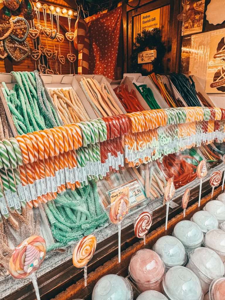 Frankfurt Christmas Markets bustling with holiday cheer, featuring traditional wooden stalls, festive lights, and seasonal decorations, with the historic architecture of the city in the background Yummy food Seeds of Travel