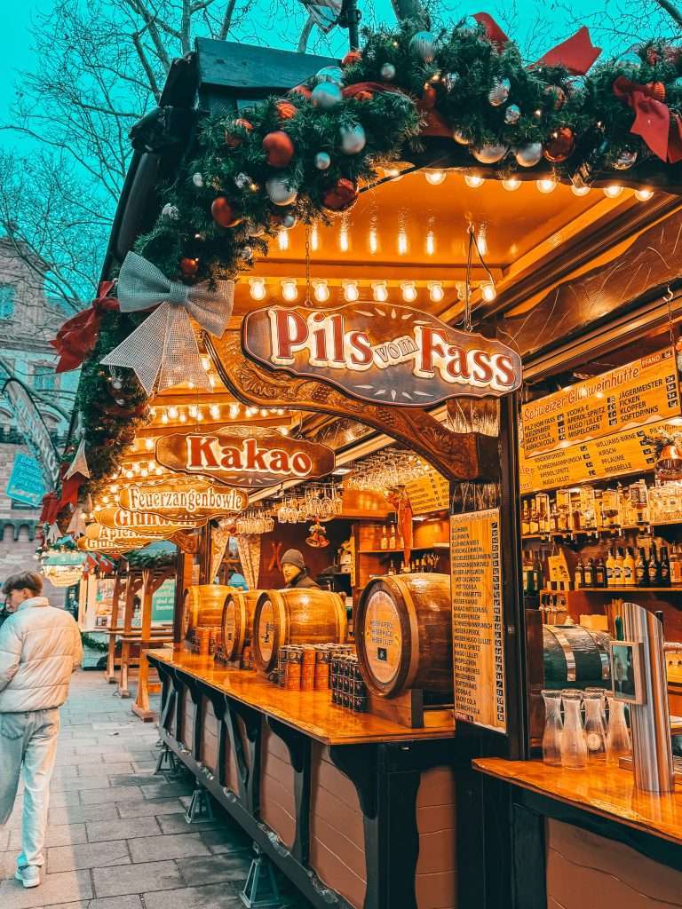 Frankfurt Christmas Markets bustling with holiday cheer, featuring traditional wooden stalls, festive lights, and seasonal decorations, with the historic architecture of the city in the background Seeds of Travel